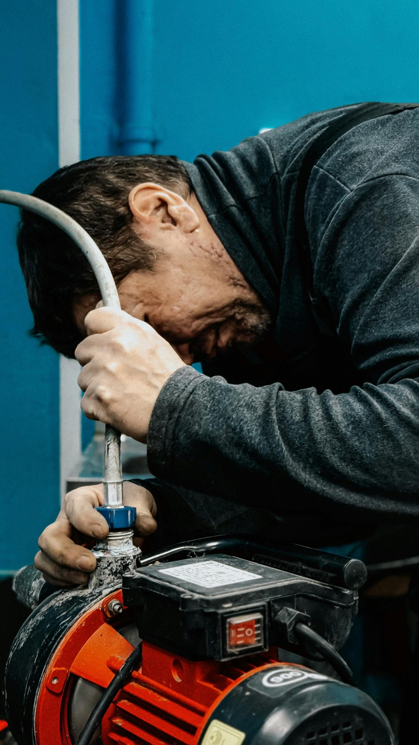 drain-cleaning A technician concentrates on adjusting a water pump indoors.